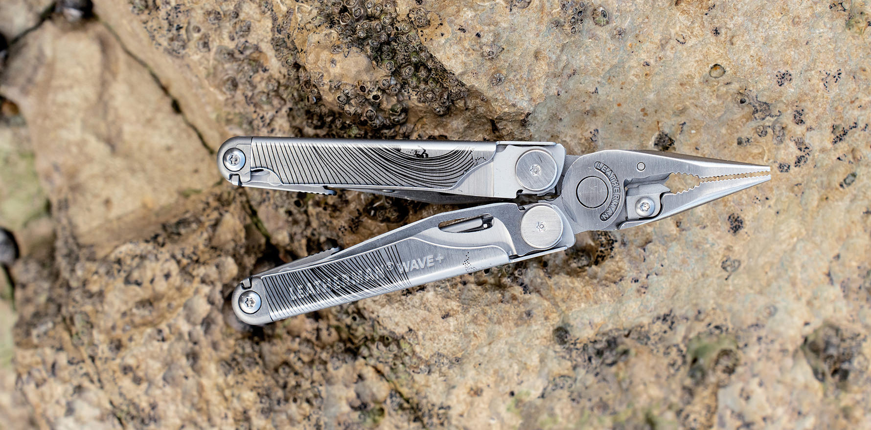 An opened stainless steel Leatherman Wave with a design for World Artist Day on the beach
