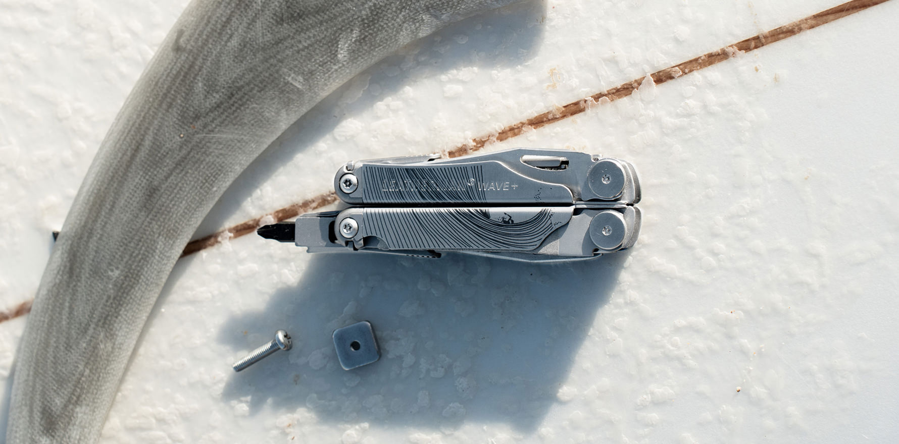 Stainless steel customised Leatherman Wave with a minimalist lined design on top of a surfboard